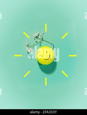 Spring Sport Komposition mit großem Tennisball in Form eines Smiley Gesichts und Blume auf blauem Hintergrund. Das Konzept der guten Laune und des Wohlbefindens Fr. Stockfoto