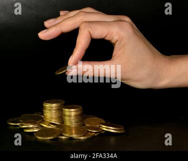 Sparkonzept durch Hinzufügen einer Goldmünze zu einem Haufen Münzen Stockfoto