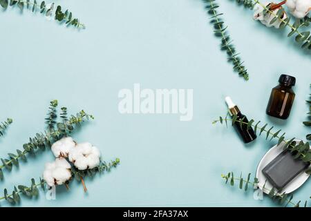 Einladungskarte Mockup mit Eukalyptuszweigen und Baumwollblumen auf blauem Hintergrund. Für die Werbung von Kosmetikprodukten Stockfoto