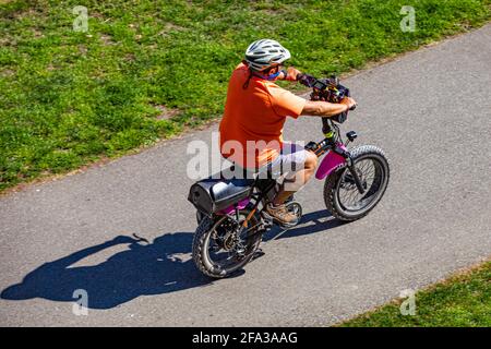 Ein Mann, der auf seinem fetten Elektroassistenten-Fahrrad auf einem Weg in die Straße fährt Steveston British Columbia, Kanada Stockfoto