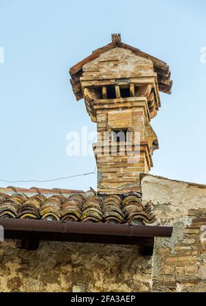 Antiker Kamin aus Ziegeln und Fliesen auf dem Dach eines Steinhauses. Abruzzen, Italien, Europa Stockfoto