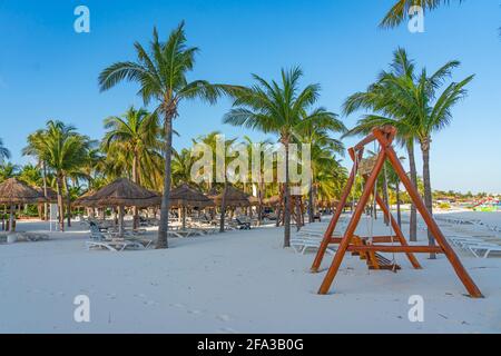 Strand mit leerer Schaukel am Morgen in cancun, Palmen und blauem Himmel Stockfoto
