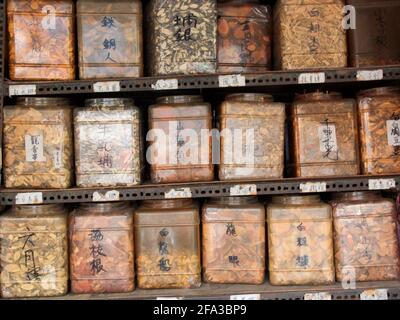 Ein Detail eines Regals, Regale mit getrockneten Blättern, Kräutern, Gewürzen in Plastikgläsern. In der alten Spice Alley in Taipei, Taiwan. Stockfoto