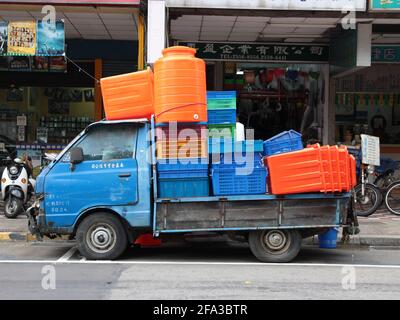 Ein kleiner, blauer Pickup, Utility Truck, voll beladen mit orangefarbenen, rosa, gelben, grünen und blauen Kunststoffbehältern. In Taipei, Taiwan. Stockfoto