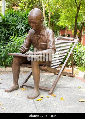 Eine schöne Bronzeskulptur eines alten Bauern, der auf einem Klappstuhl sitzt und auf einem Pad zeichnet. In Taipei, Taiwan. Stockfoto