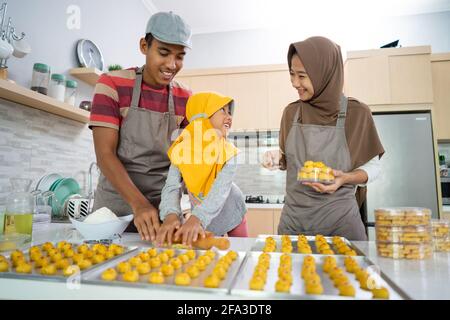 Glückliche muslimische Familie mit Hijab, die zusammen Nastar-Kuchen machen Stockfoto