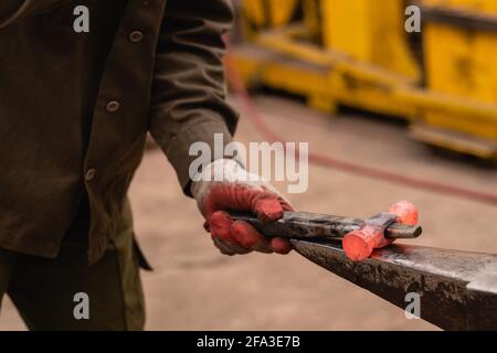 Traditionelle Metallbearbeitung in einer Schmiede. Nahaufnahme der Bearbeitung eines Werkstücks mit herkömmlichem Schmieden. Stockfoto