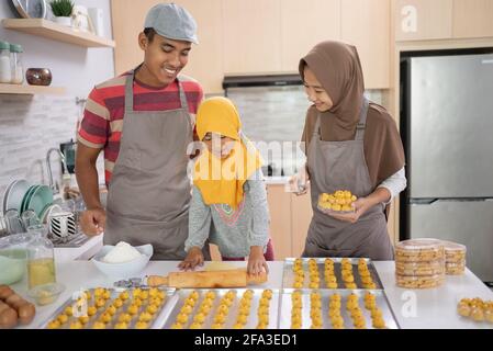 Glückliche muslimische Familie mit Hijab, die zusammen Nastar-Kuchen machen Stockfoto
