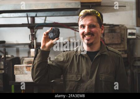 Ein Schmied hält ein Erz in der Hand. Traditionelle Metallbearbeitung in einer Schmiede. Stockfoto