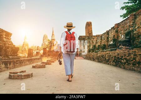 Junge Frau touristisch zu Fuß mit kompakter Fotokamera durch Ayutthaya Wat Phra RAM alten Ruinen in Thailand. Geschichte, Tourismus, Sightseeing-Konzept. Stockfoto