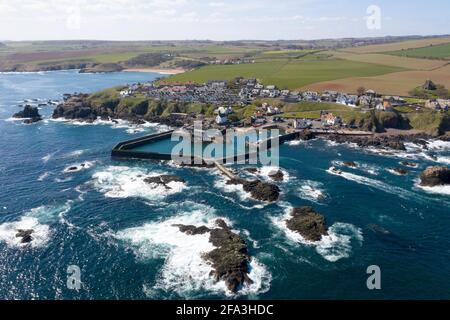 Luftaufnahme zeigt ein Fischerboot, das zum Hafen von St. Abbs an der Küste von Berwickshire, Schottland, Großbritannien, zurückkehrt. Stockfoto