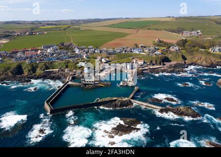 Luftaufnahme zeigt ein Fischerboot, das zum Hafen von St. Abbs an der Küste von Berwickshire, Schottland, Großbritannien, zurückkehrt. Stockfoto