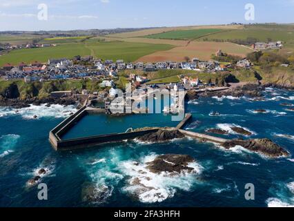 Luftaufnahme zeigt ein Fischerboot, das zum Hafen von St. Abbs an der Küste von Berwickshire, Schottland, Großbritannien, zurückkehrt. Stockfoto