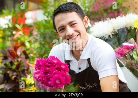 Freundliche asiatische Florist oder Verkäufer in einem Blumenladen mit einem Blumenstrauß Stockfoto