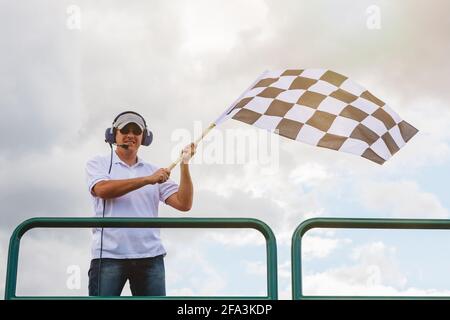 Mann winkt eine karierte Flagge an der Ziellinie von Das Rennen Stockfoto