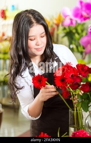 Freundliche asiatische Floristin oder Verkäuferin in einem Blumenladen Stockfoto