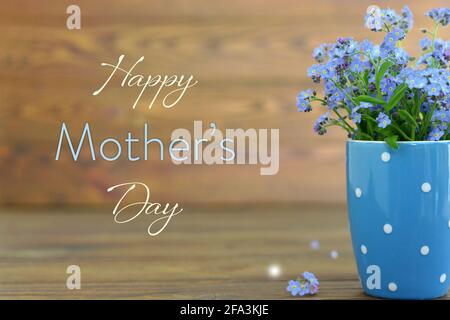 Muttertagskarte mit Blumen im Becher auf Holz Hintergrund Stockfoto