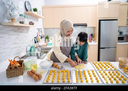 muslimische Mutter während ramadan Aktivität mit ihrer Tochter machen ein Nastar Kuchen zusammen Stockfoto