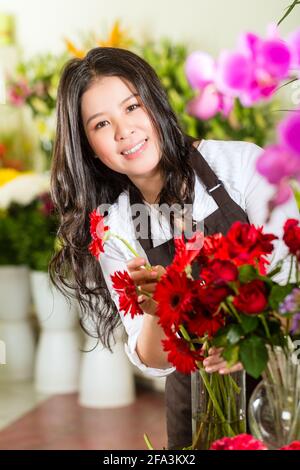 Freundliche asiatische Floristin oder Verkäuferin in einem Blumenladen Stockfoto