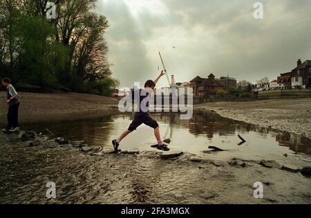 Ein Junge springt auf der Themse in Isleworth West London Der Fluss teilt sich in zwei bei Isleworth und diesem Teil Ist in der Regel schwierig zu überqueren, auch bei Ebbe pic Von andrew buurman Stockfoto