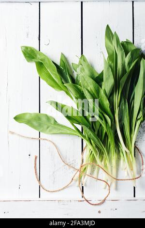 Frische Ramson-Blätter (Allium ursinum) auf einem weißen Holztisch. Stockfoto