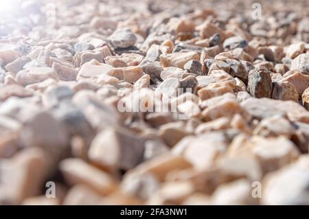 Scharfe Granitfelsen bei Sonnenschein mit Hintergrundbeleuchtung. Hintergrund und Texturkies am Strand am Meer Stockfoto