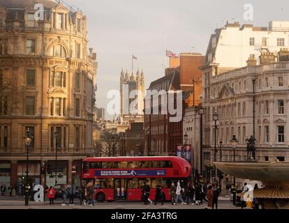 London, Greater London, England - 17 2021. April: Doppeldeckerbus in der Nähe des Trafalgar Square mit den Houses of Parliament im Hintergrund und Union Jacks Stockfoto