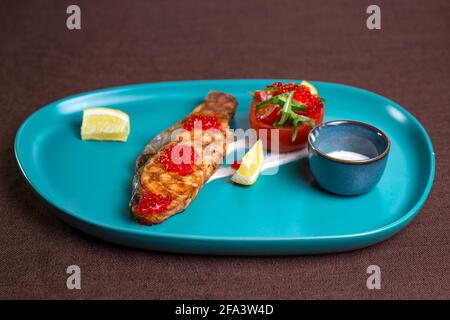 Lachssteak mit Kaviar auf einem blauen Teller. Stockfoto