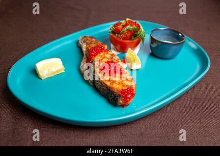 Lachssteak mit Kaviar auf einem blauen Teller. Stockfoto