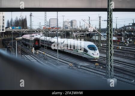 MÜNCHEN, DEUTSCHLAND - 21. Apr 2021: Auf den Gleisen steht ein ICE mit der Stadt München im Hintergrund. Die deutsche Eisenbahn ist für Verspätungen bekannt. Stockfoto