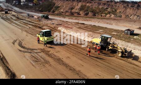 Warschau, Polen 04.10.2019 - Arbeiter, die schwere Maschinen zum Nivellieren von Boden benutzen. Luftaufnahme von Drohne auf der Baustelle in der Nähe von Warschau, Polen. Stockfoto