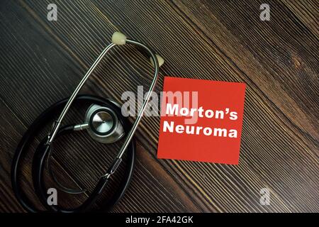 Mortons Neuroma schreibt auf Haftnotizen, die auf einem Holztisch isoliert sind. Stockfoto