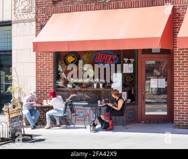 ASHEVILLE, NC, USA-11 APRIL 2021: Die Twisted Crepe Kaffee- und Konditorei in der Innenstadt. Drei Personen sitzen an Tischen im Freien. Stockfoto