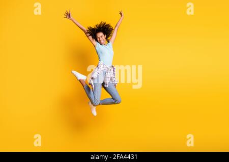 In voller Länge Foto von glänzenden funky dunkle Haut lockiges Mädchen Gekleidet blau T-Shirt springen leeren Raum isoliert gelbe Farbe Hintergrund Stockfoto