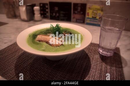 Nahaufnahme einer Schale mit hellgrünem Matcha-Ramen Garniert mit Schweinebraten und eingelegten Algen Stockfoto