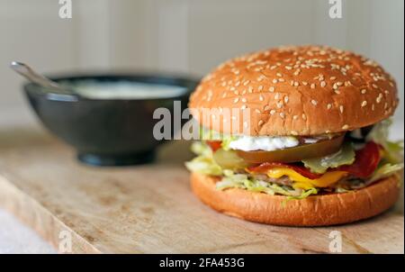 Rustikaler handgemachter Hamburger mit Sauce auf dem Tisch. Stockfoto