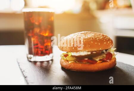 Rustikal handgemachter Hamburger und Cola auf dem Tisch. Stockfoto