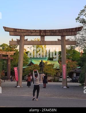 Osaka, Japan - 31 2020. Oktober: Nachmittagsansicht eines Joggers, der sich vor dem Torii-Tor am Eingang des Hokoku-Schreines erstreckt, mit der Statue von Stockfoto