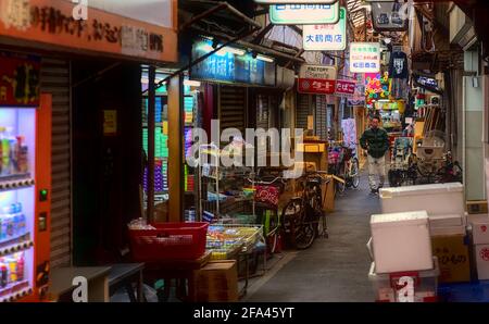 Osaka, Japan - 5 2020. November: Ein Mann mittleren Alters, der durch eine schmale, überdachte Einkaufsstraße im Tsuruhashi-Viertel von Osaka geht Stockfoto