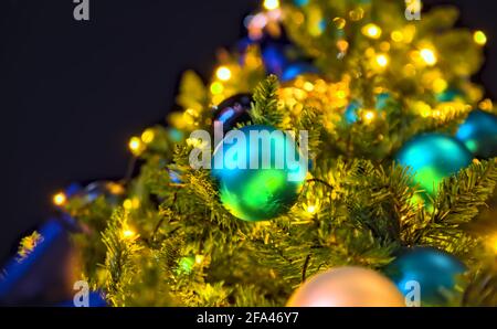 Nachtansicht eines kugelblauen Weihnachtsornaments auf einem Weihnachtsbaum von gelben Lichtern beleuchtet Stockfoto