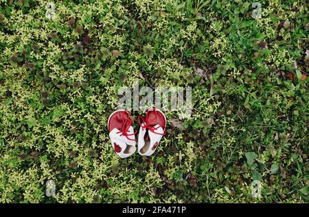 Leder Baby Vintage Retro weiß und rot Stiefel mit Schnürsenkeln auf grünem Gras, Draufsicht, erste Kleinkind Kleinkind Schuhe Stockfoto