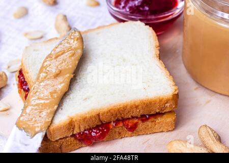 Hausgemachtes Sandwich zum Frühstück mit frischer knackiger Erdnussbutter und Erdbeergelee auf hellem Hintergrund. Stockfoto