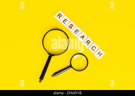 Schwarze Lupe mit Forschungstext auf hellgelbem Hintergrund mit Kopierraum. Statistische Analyse und wissenschaftliches Suchkonzept. Stockfoto