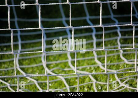 Nahaufnahme eines weißen Seilnetzes, das den Fußball verhindert Ball vor dem Entweichen durch den Boden der Ständer auf Ein Spielfeld Stockfoto