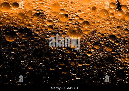 Nahaufnahme einer orangefarbenen Substanz mit Blasen und Wassertröpfchen, die einen starken Farbverlauf von kräftigem Orange zu Schwarz zeigt Stockfoto
