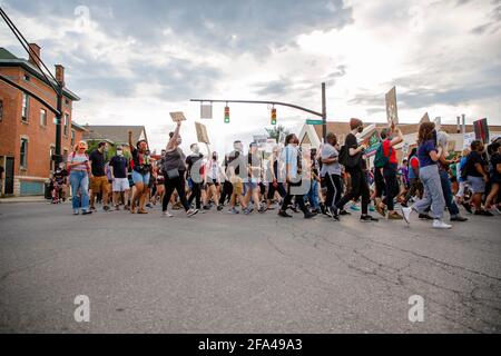 Eine große Gruppe von Protestierenden marschiert friedlich die Straße entlang Schilder Stockfoto