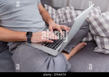 Der Mann arbeitet für Laptops, die in Nahaufnahme auf den Couchhänden sitzen Stockfoto