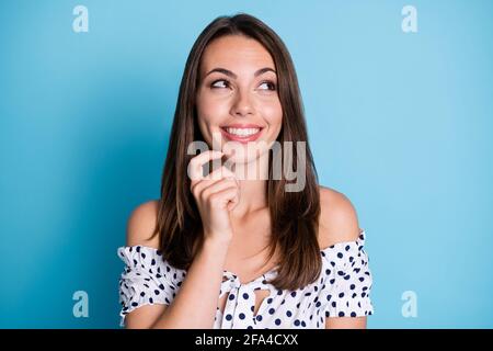 Foto von neugierigen smart junge Mädchen Finger Kinn leer aussehen Space tragen gepunktete Bluse isoliert blauen Hintergrund Stockfoto