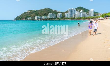 Sanya China , 25. März 2021 : Chinesische Touristen gehen barfuß am weißen Sandstrand von Dadonghai an einem sonnigen Tag auf der Insel Sanya Hainan China Stockfoto