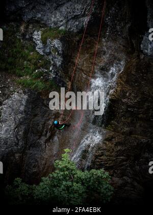 Junger Mann abseilen von vertikalen Felswand Klippe, Abenteuer Sport Spaß Aktivität an Stuibenfaelle Stuiben Wasserfälle in Breitenwang Reutte T Stockfoto